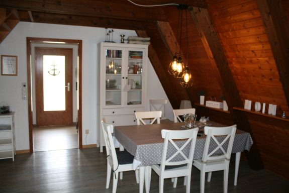 Heller Essbereich mit Holzmöbeln und Blick auf eine Eingangstür.